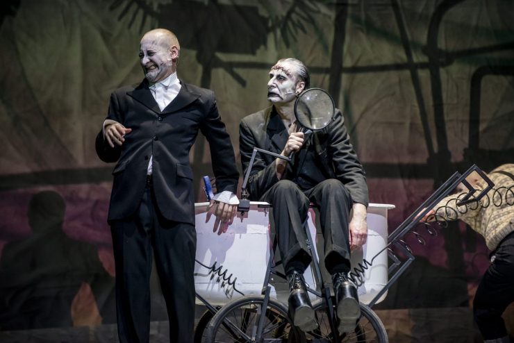 Od lewej Wiktor Frankenstein (Kiljan), monstrum (Studniak) i Igor (Picher). Monstrum siedzi na wózku laboratoryjnym, trzyma szkło powiększające. Wiktor oparty o wózek plecami, krzywi twarz. Obydwoje patrzą w jednym kierunku. Igor wychodzi z kadru z prawej strony.