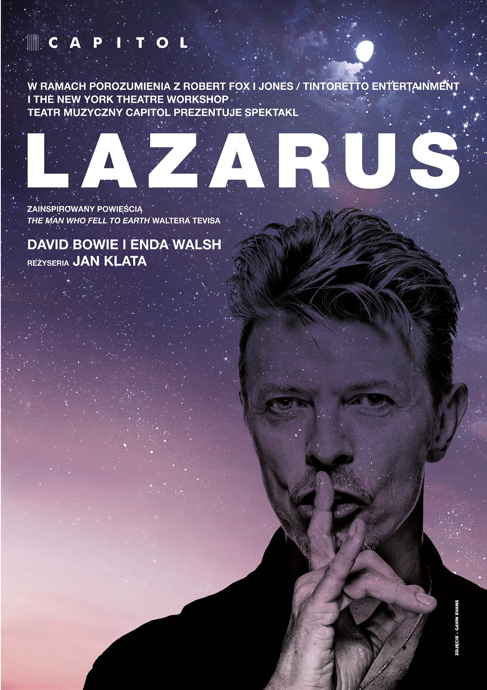 Plakat musicalu Lazarus. Na fioletowym tle rozgwieżdżonego nieba ujęcie Dawida Bowiego do ramion. Artysta kładzie na ustach palce wskazujący w geście nakazującym milczenie. Nad jego głową widnieje duży, biały napis LAZARUS, poniżej informacje o właścicielach licencji i realizatorach.